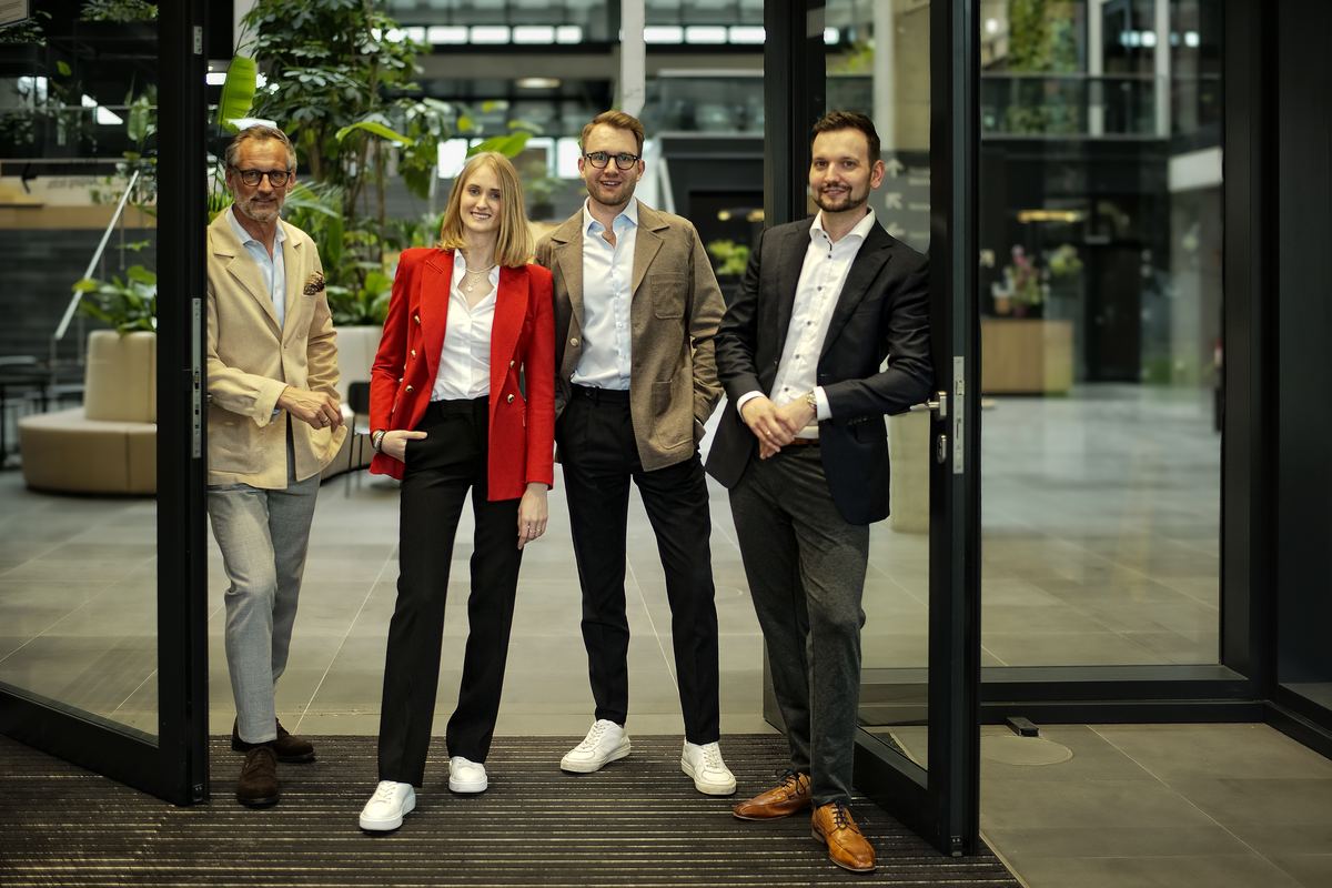 Das Team von Hemmers, Wagner & Kollegen steht in der offenen Eingangstür des Büros in der HafenCity